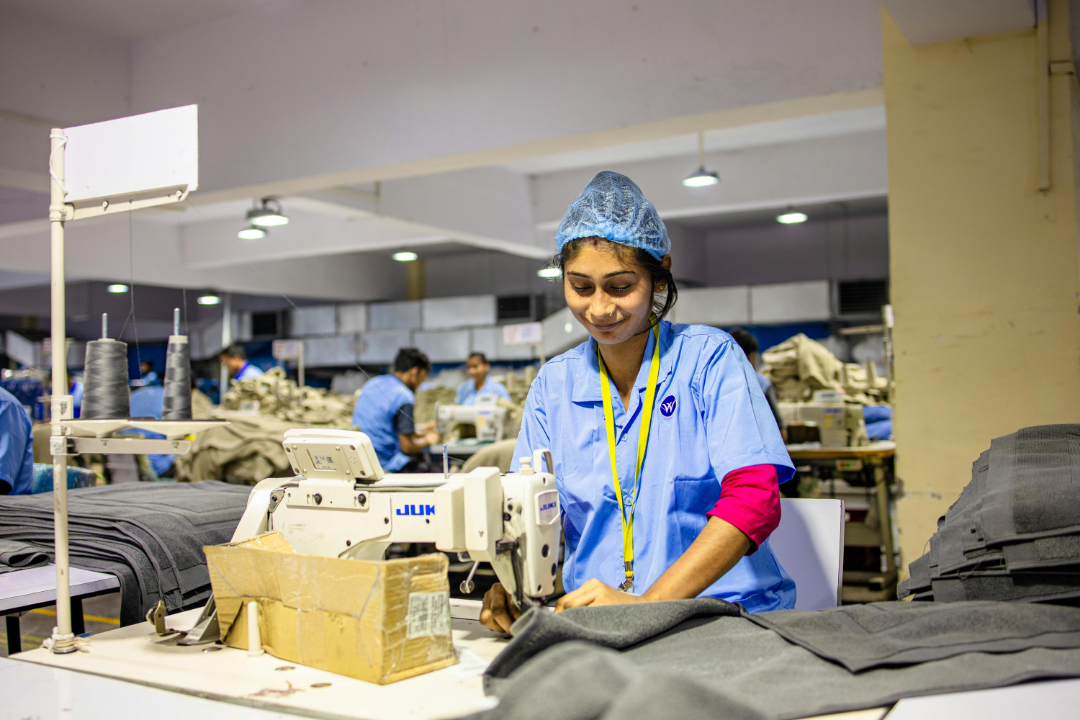 Apparel manufacturing — garment worker stitching fabric on an industrial sewing machine