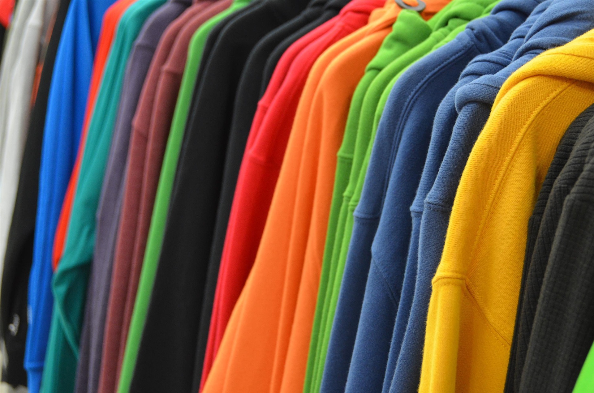 Row of colorful hoodies and sweatshirts on hangers